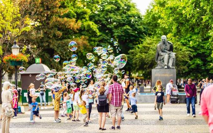 Gente a passeggio lungo il viale alberato di piazza Hviezdoslav in un pomeriggio d’estate