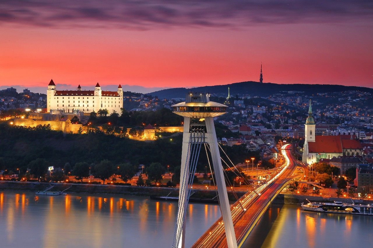 La terrazza dell’UFO sul Ponte SNP al crepuscolo, con il castello illuminato sull’altra riva del Danubio